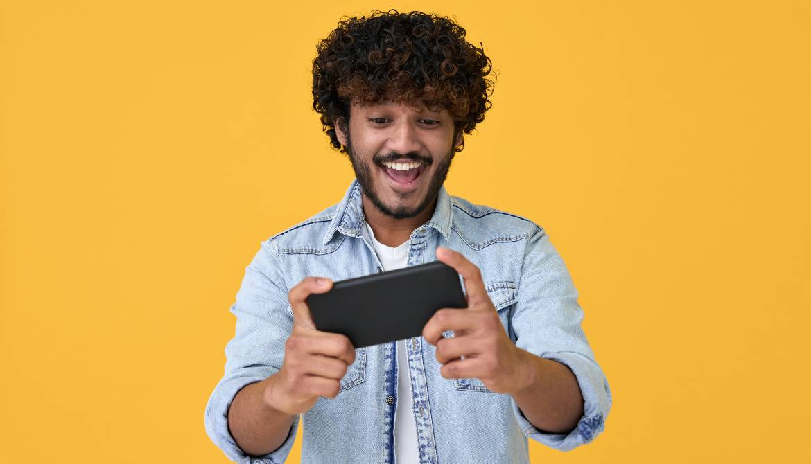 excited young Indian man looking at a phone