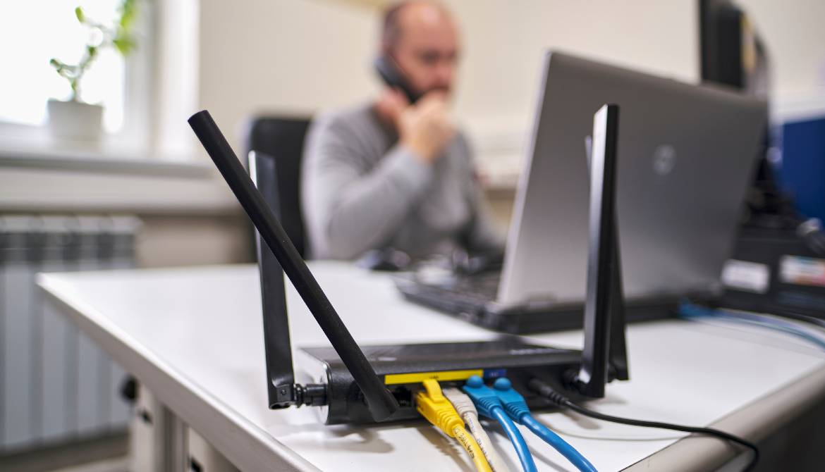 wireless router with ethernet cables and man working in the background