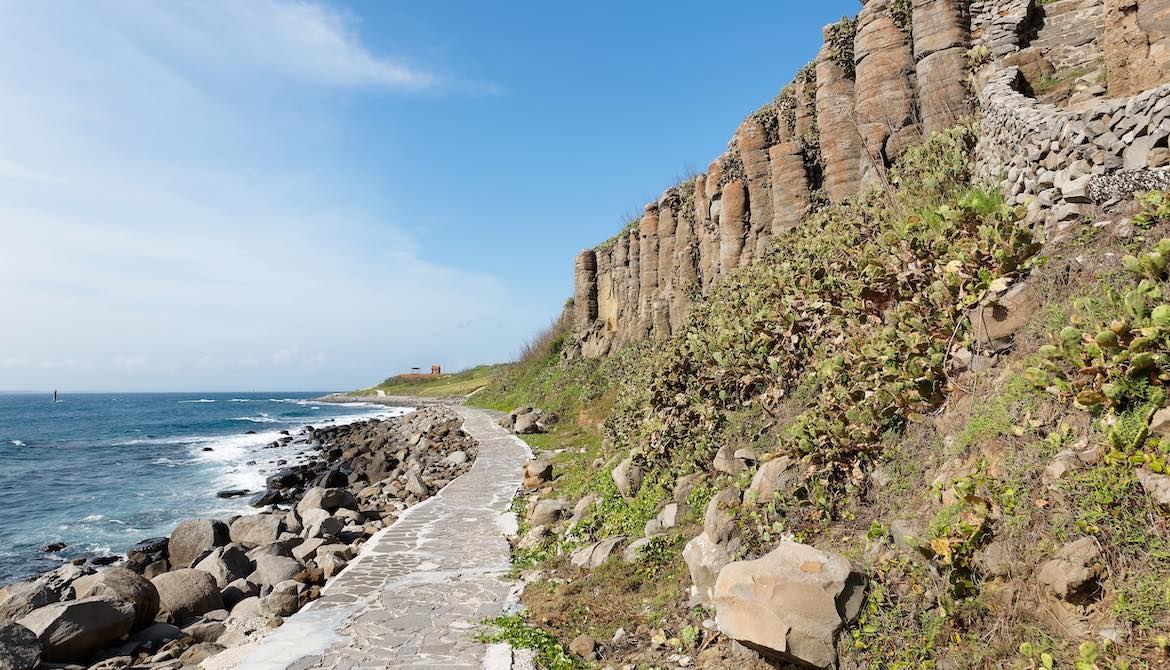 stone paved pathway runs along shore at cliffside beach