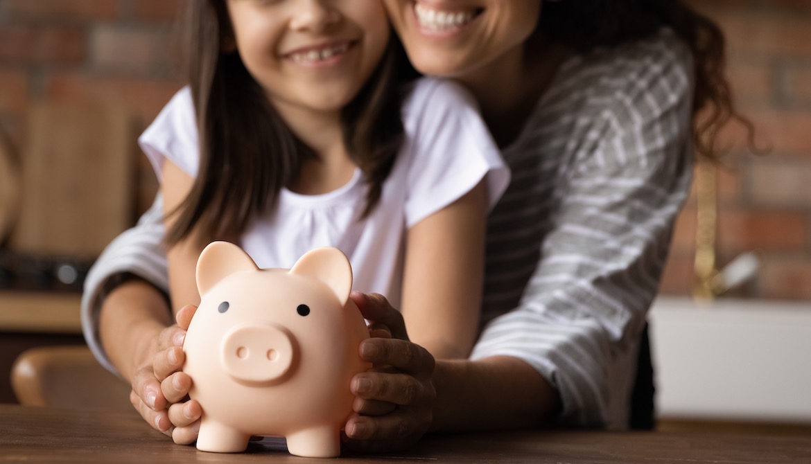 happy mother and young daughter holding piggy bank