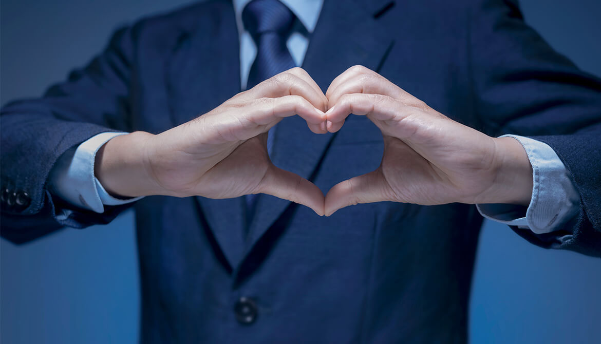 hands making heart symbol in front of man in suit