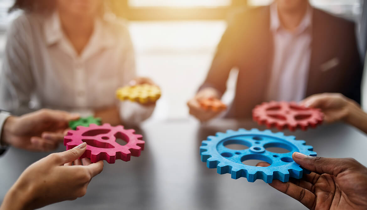 hands bringing gears together at a table