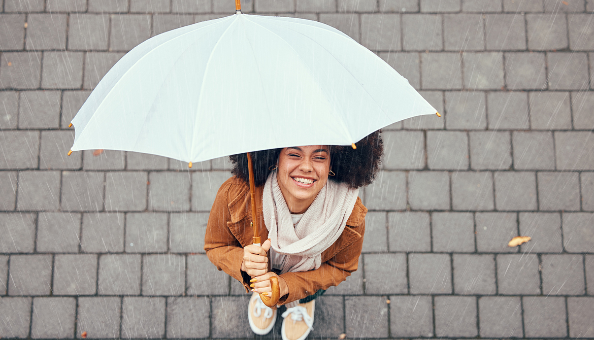 woman standing under an umbrella looking up smiling