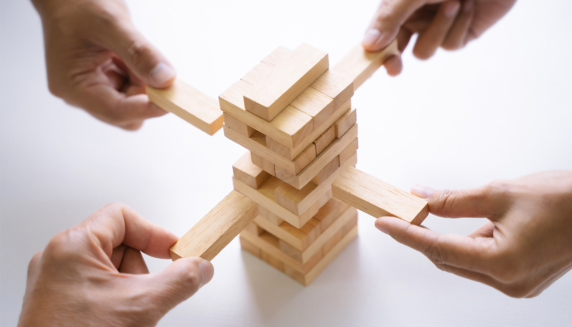 four hands playing Jenga game