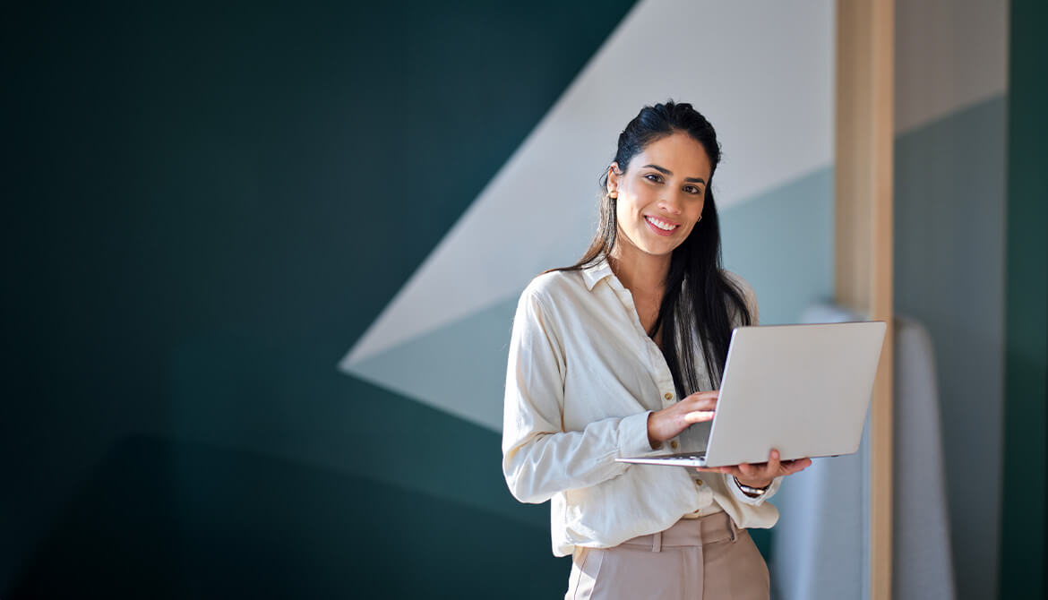 smiling woman standing holding a laptop