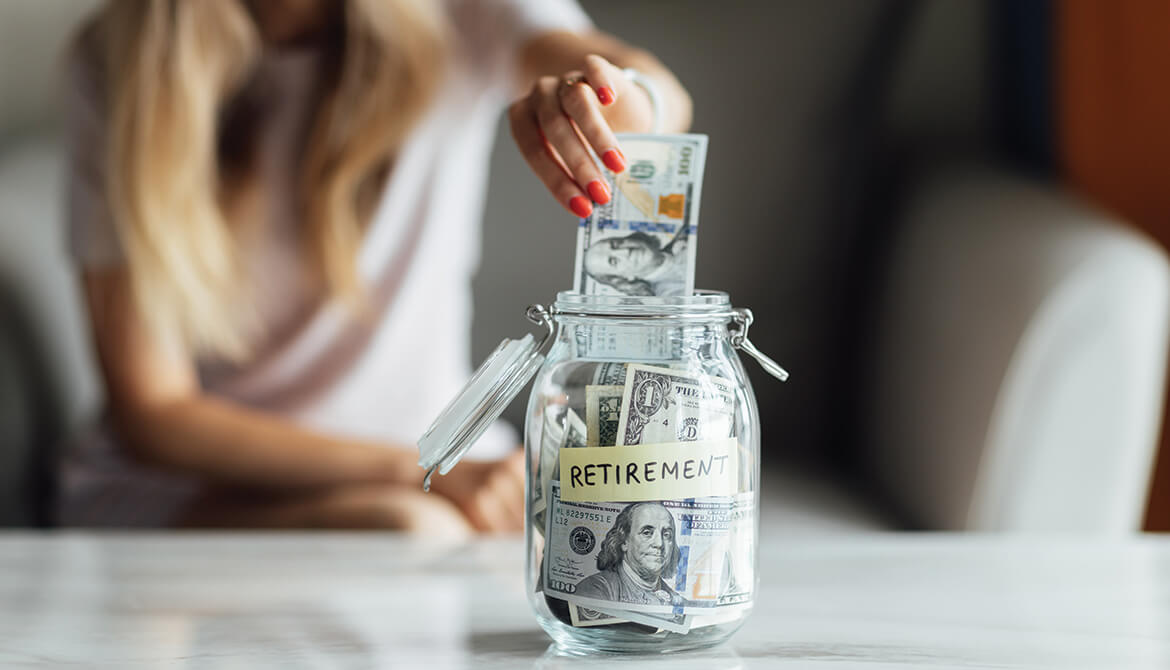 woman putting one hundred dollar bill in a jar marked Retirement