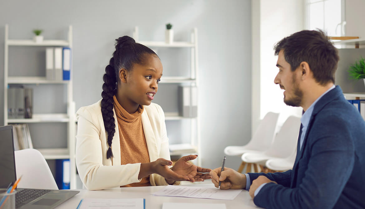 2 individuals talking while one is writing on a paper