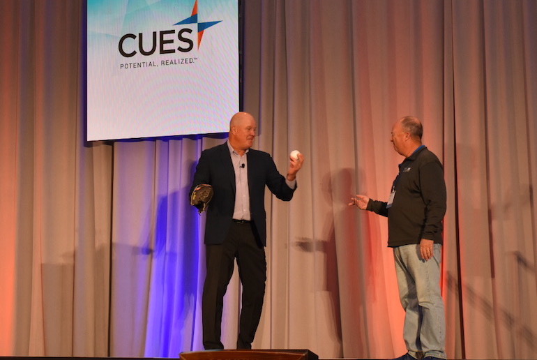 Jim Abbott playing catch on stage with Brown Simpson of Family Trust FCU at 2022 CUSE Directors Conference