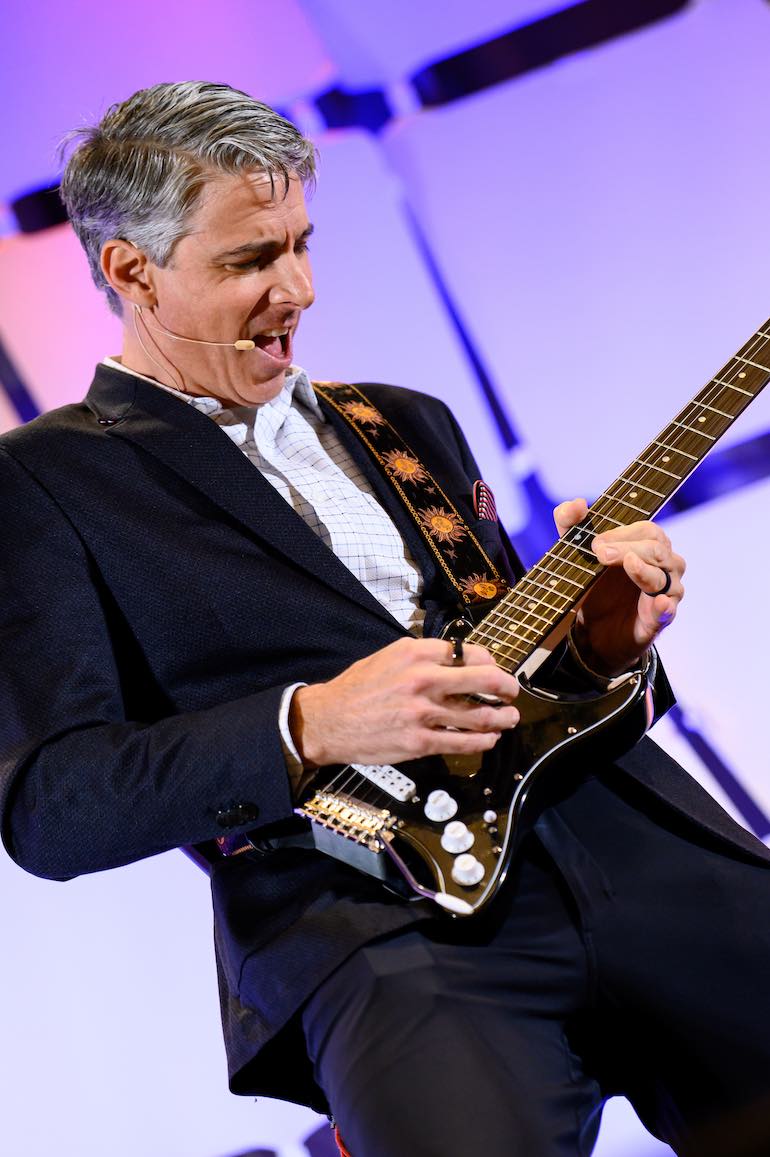 Directors Conference speaker Manley Feinberg plays electric guitar.