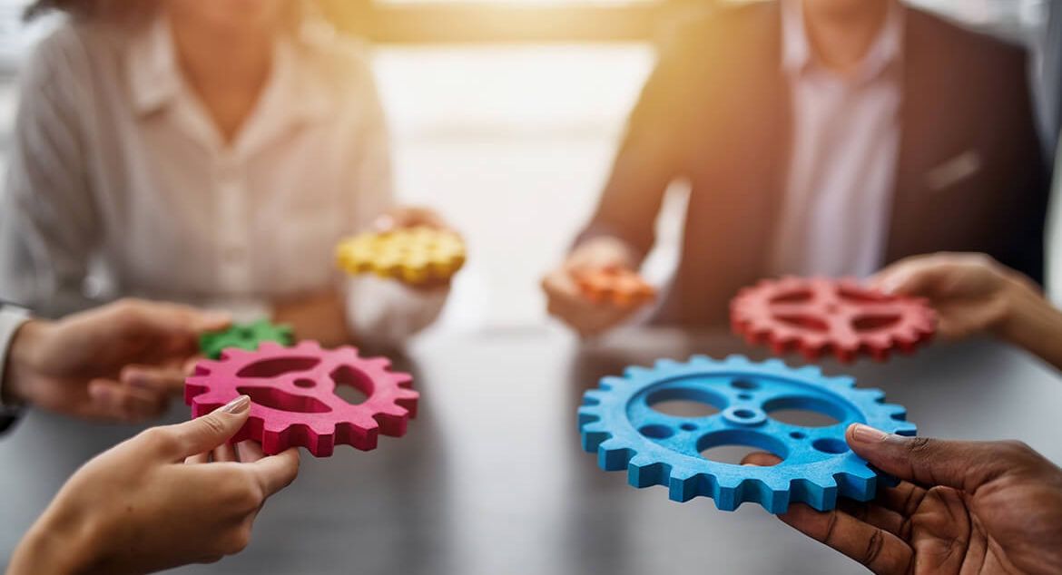 hands bringing gears together at a table