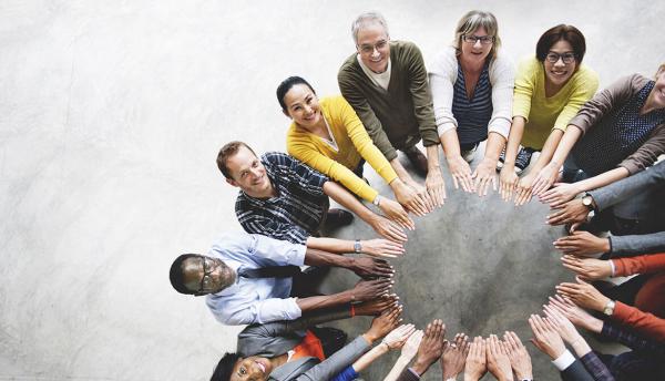 diverse group of happy people putting their hands into the center to form a circle