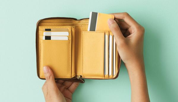 hand pulls payment card out of tan and yellow leather wallet
