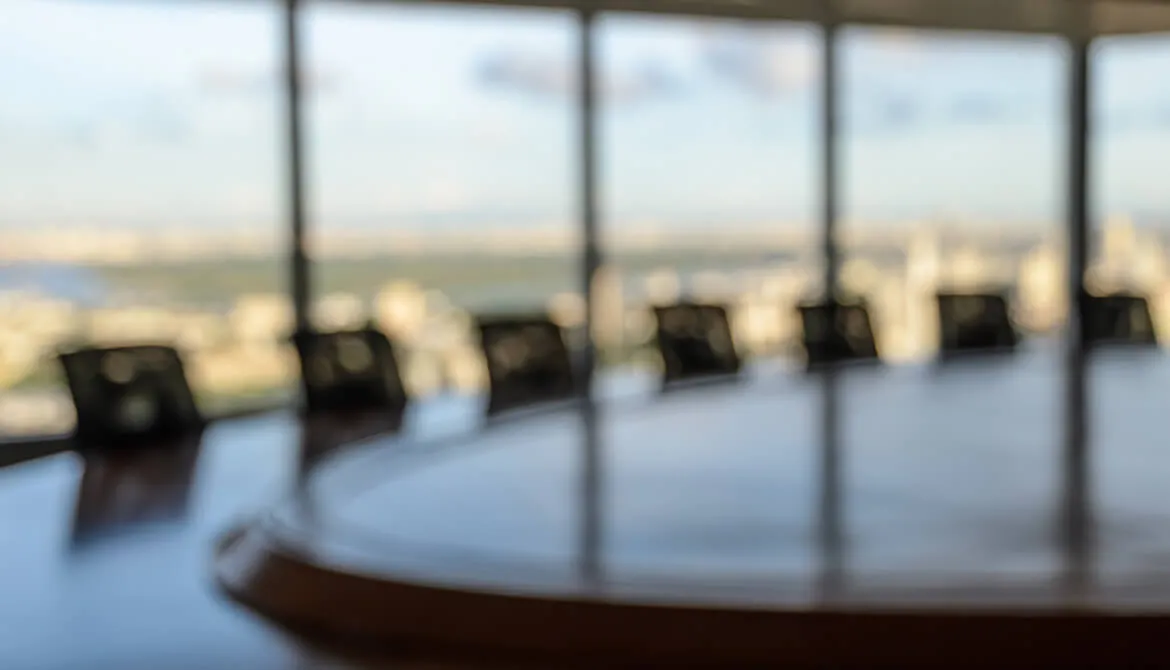 blurry image of board room table chairs with windows in background