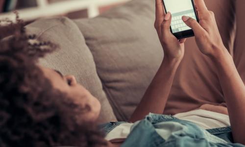young person on couch with smart phone