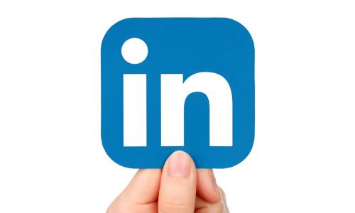 Hand holding up a blue LinkedIn icon
