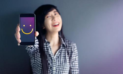 happy woman with smiley face on her cell phone screen showing her good experiences