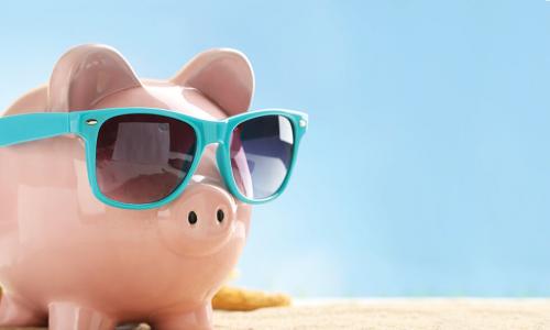 Piggy bank wearing sunglasses on the beach