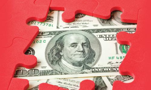 $100 bills underneath a partially completed red puzzle