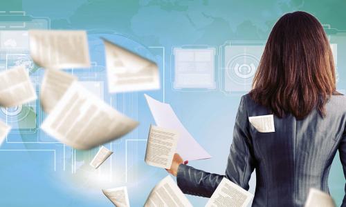 businesswoman surrounded by a swirl of papers and digital documents