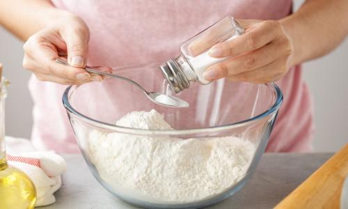 woman adding salt to dough