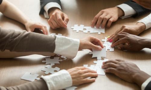 diverse group of business people putting together a puzzle on a table
