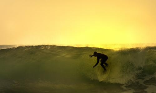 surfer catching a wave at sunset