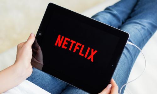 woman holding a tablet with the Netflix logo