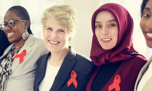 diverse group of women standing shoulder to shoulder wearing orange partnership ribbons