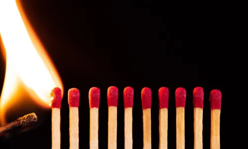 lit match igniting a line of matches