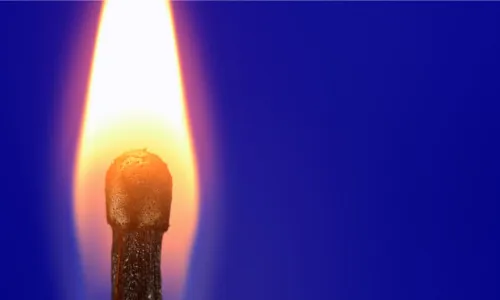 A burning match on a blue background
