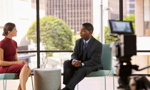 female TV anchor interviewing an African American businessman on camera