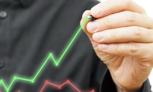 Man in black shirt drawing a green financial graph above an existing red financial graph