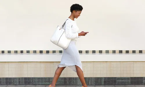 happy young woman walking and texting