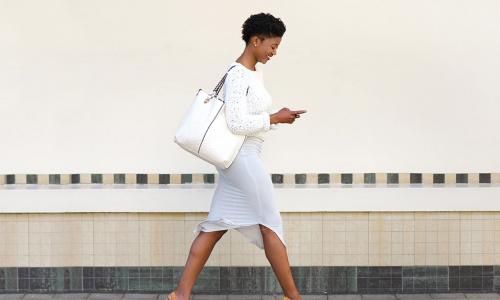happy young woman walking and texting
