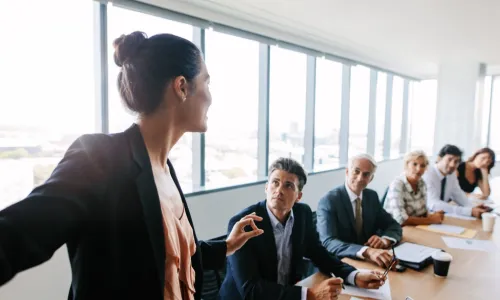 female asian executive presenting to a group around a board room table