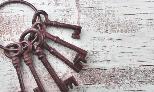 ring of old iron keys on a white wooden background