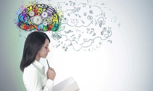 business woman studies a notebook with a colorful brain full of gears above her head