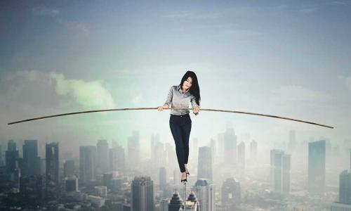 businesswoman holding a stick to balance while walking on a tightrope above a city