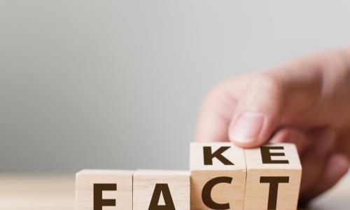 hand flips wooden blocks to change the word fake to spell fact