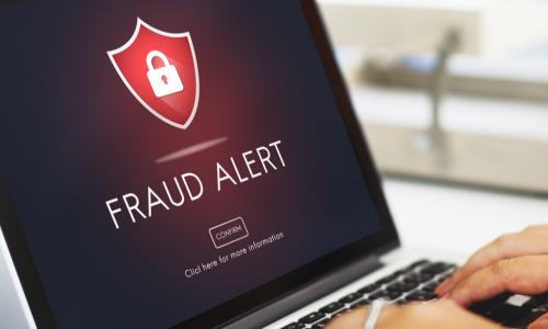 hands typing on laptop with screen displaying fraud alert