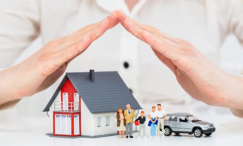 credit union insurance agent protects model house family and car with her hands