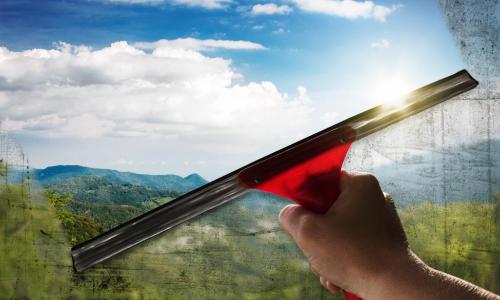 window squeegee washing a window to clear with a beautiful landscape