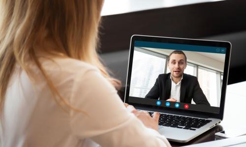 Woman using laptop to teleconference with a male executive