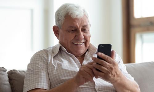 older man using smartphone on couch
