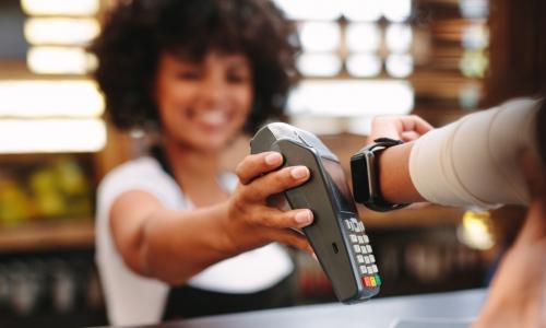 smiling clerk accepts contactless payment via apple watch