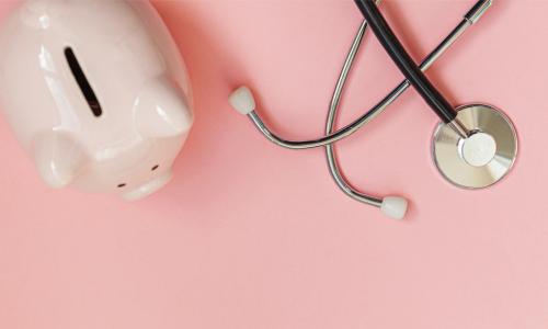 piggy bank and stethoscope on a pink background