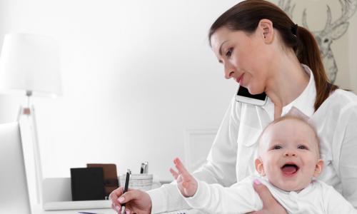 professional mom working from home while holding laughing baby