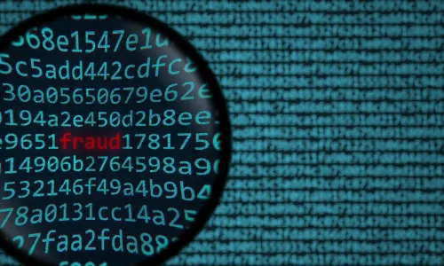the word fraud showing in red among data under magnifying glass
