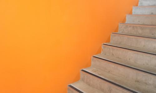 wooden staircase with an orange wall