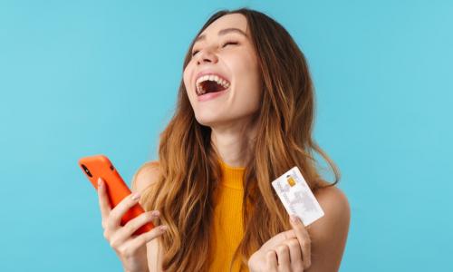 delighted woman with credit card and smartphone